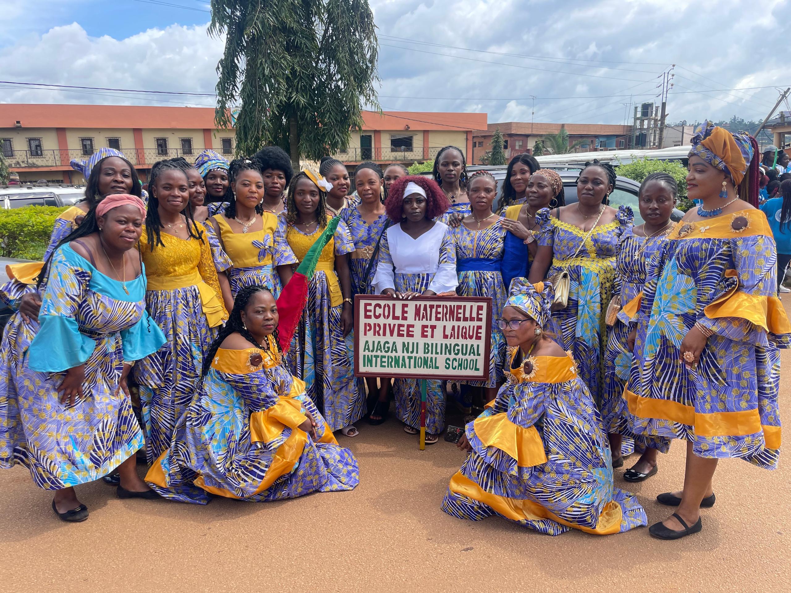 Ajaga Nji gathering in yellow and blue dress holding the nursery school sign